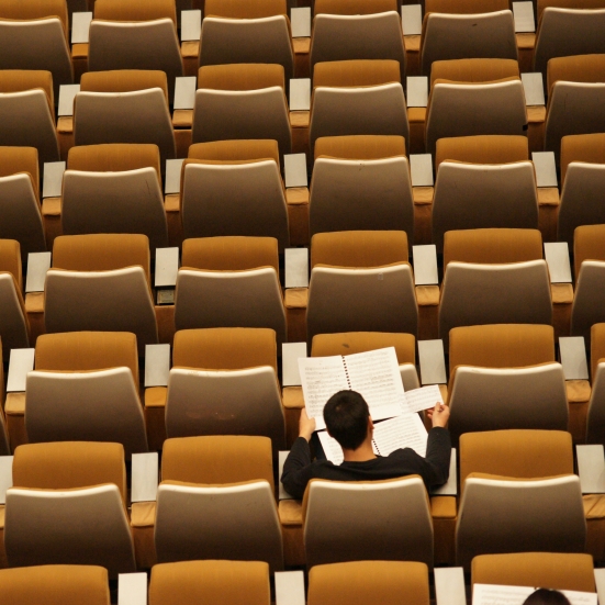 Studerende der sidder og læser i en tom foredragssal